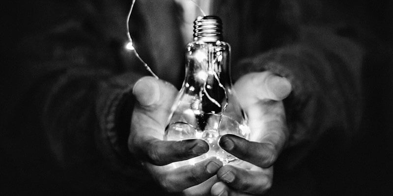 Cupped hands holding a light bulb