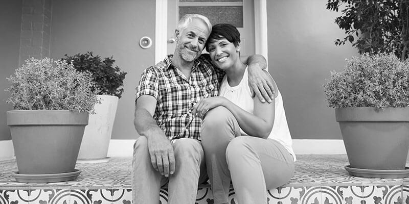 Happy couple sat on a large pretty doorstep