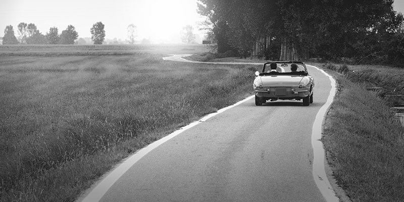 Couple driving down a country road in a classic car