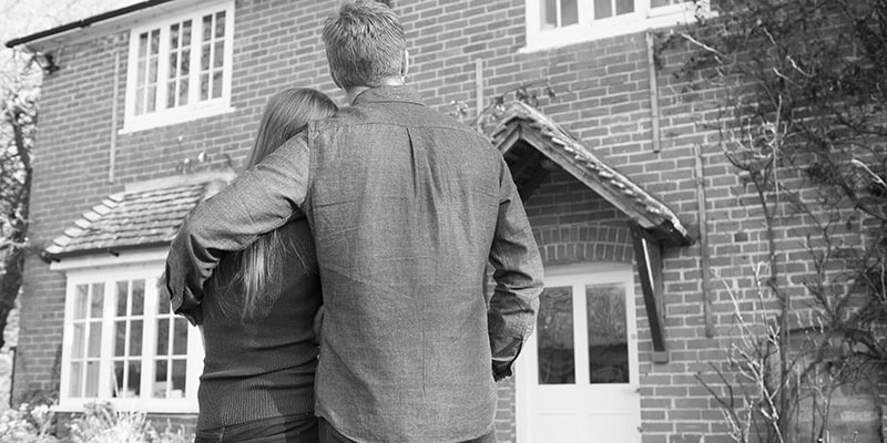 Backs of couple viewing house exterior