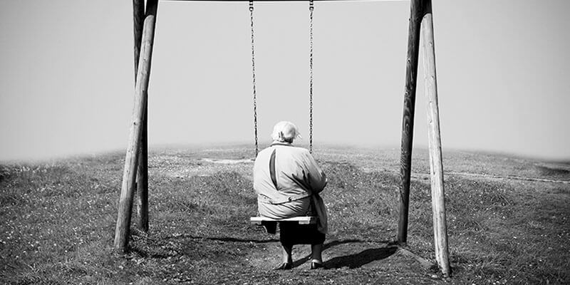 Elderly woman sat on swing overlooking mist