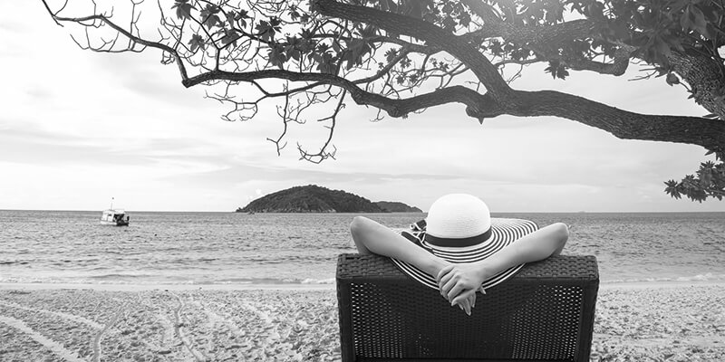 Relaxed retiree at on a Rattan seat looking out at the ocean