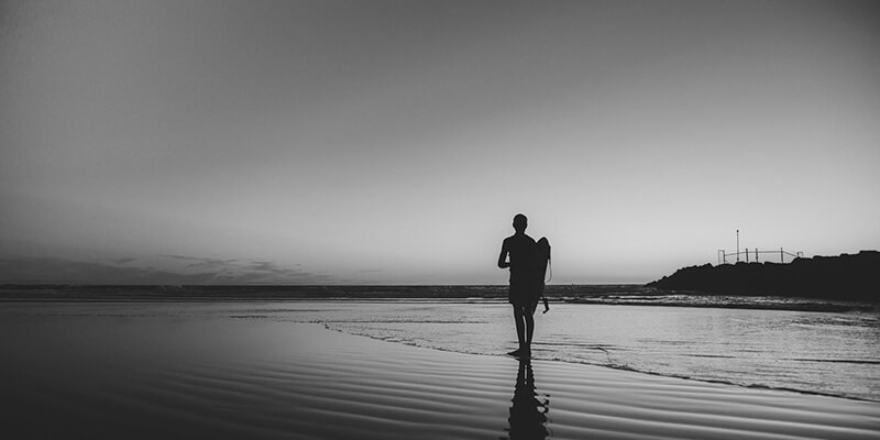 Silhouette of surfer walking into the ocean