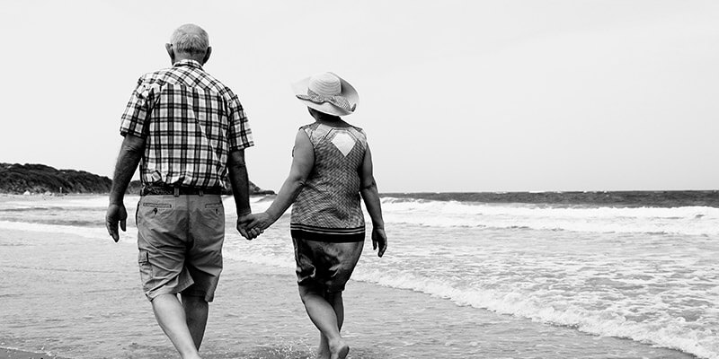 Retired couple holding hands while paddling through the sea
