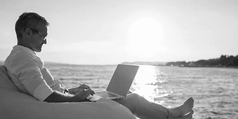 Relaxed man working on his laptop with a view of the sea