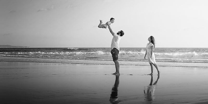 Couple raising a child in the air on a beach