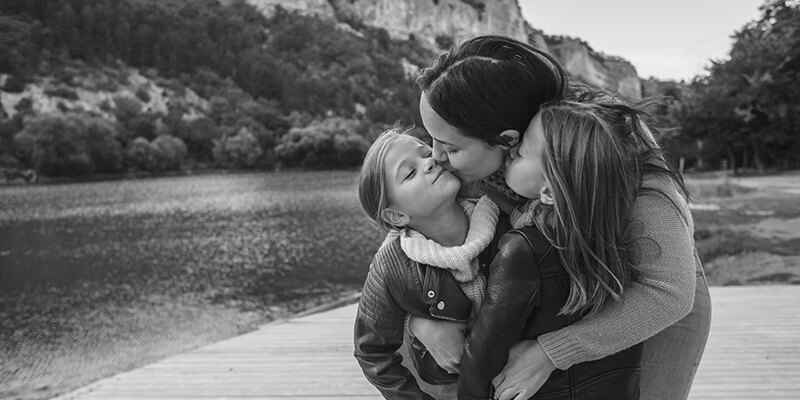 Mother embracing daughters with a kiss