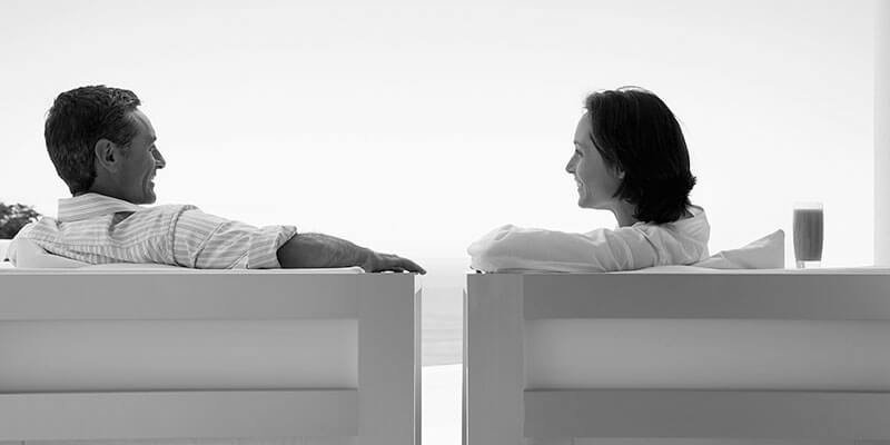 Couple sat on facing chairs having a jovial conversation